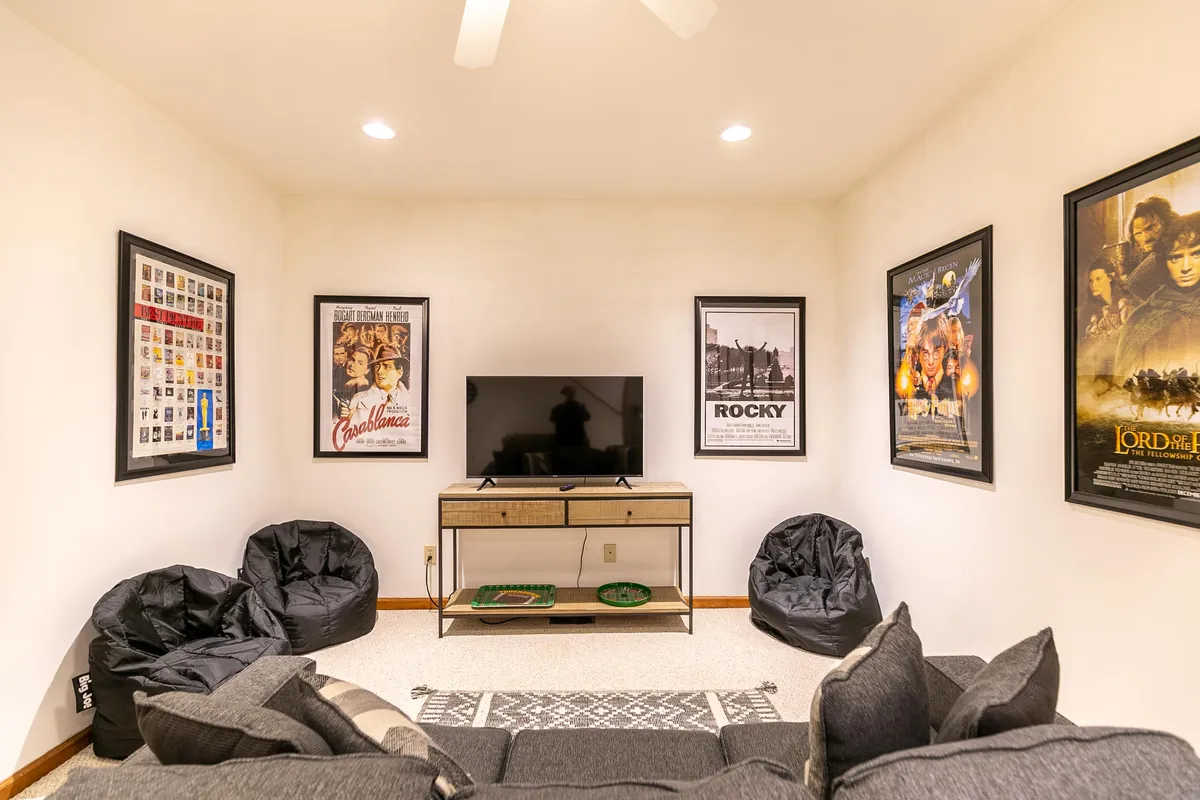 The image presents a casual entertainment area with a large TV, movie posters, bean bag chairs, and a comfortable sofa. It's a prime spot for movie marathons, gaming, or simply unwinding with friends.