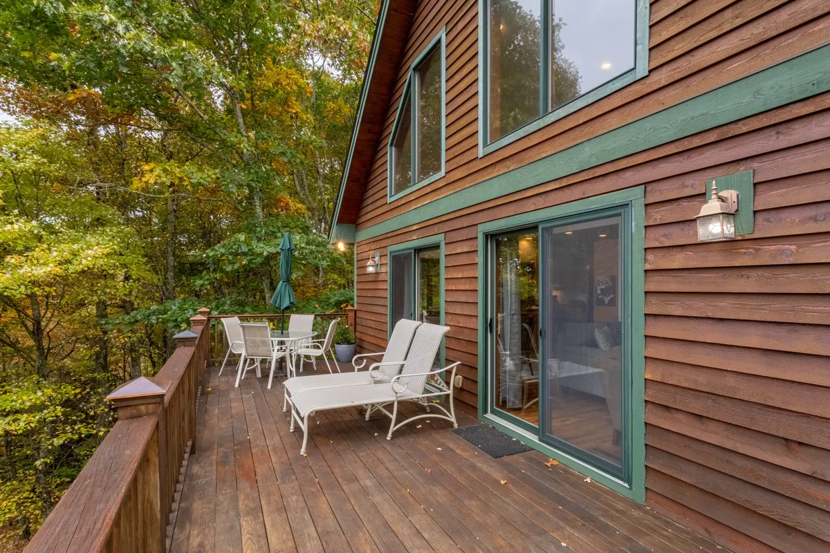 A deck area with inviting outdoor seating is surrounded by tall trees, creating a private oasis ideal for relaxation and connection with nature. The scene suggests both sunny afternoons and starlit evenings outdoors.