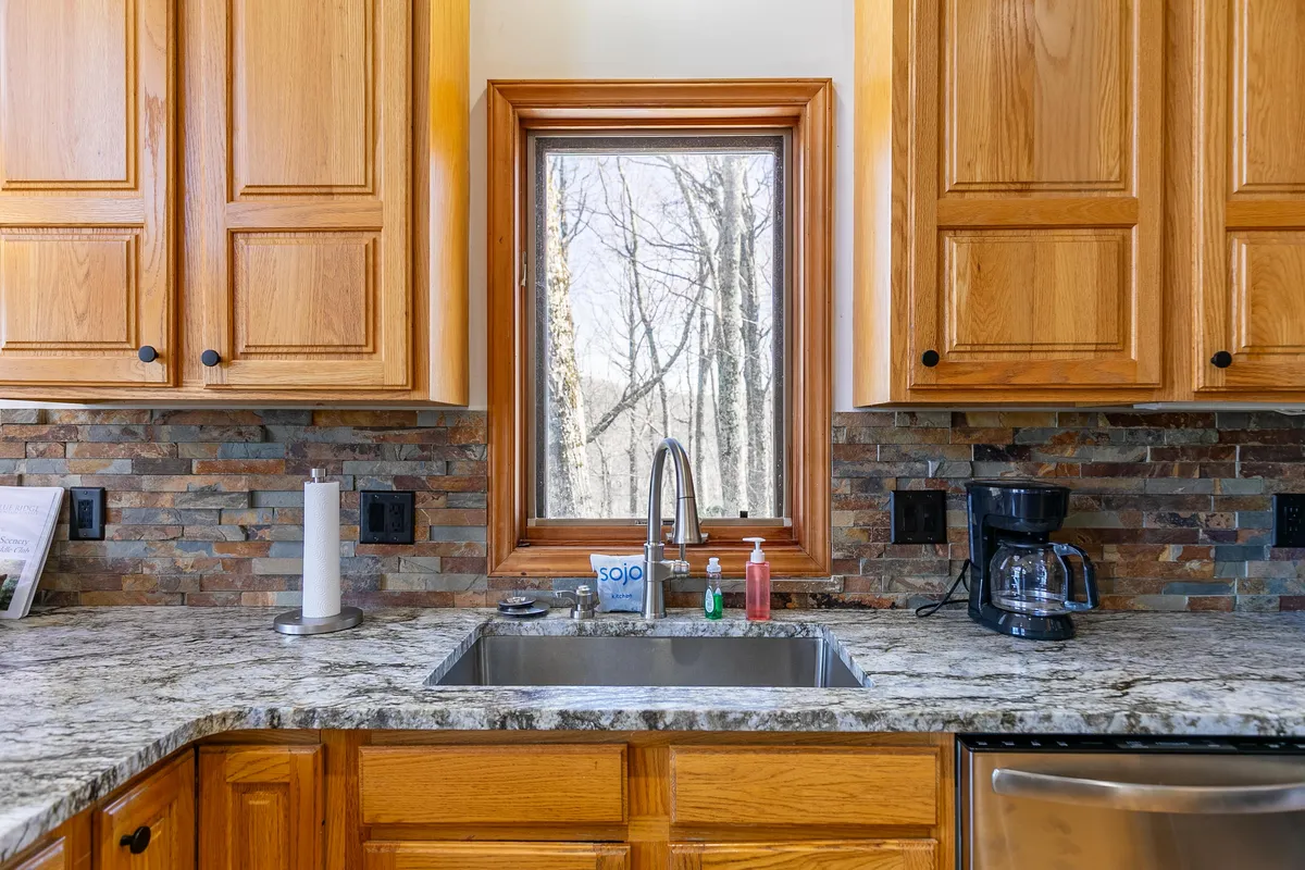 A welcoming kitchen scene with a large window offering sunrise views, warm cabinetry, and a coffee maker on the countertop. The room is filled with natural light, evoking a sense of morning readiness for an active day outdoors.