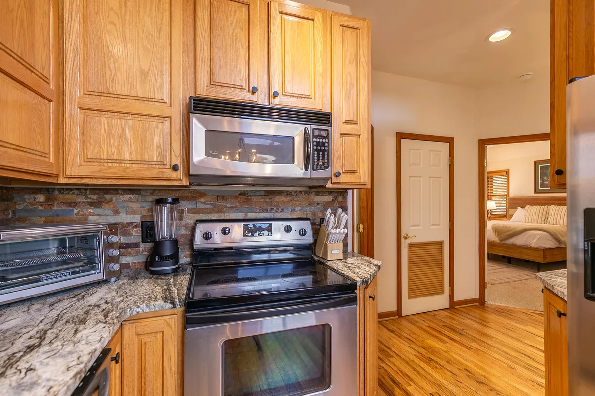 A close-up of the kitchen area, featuring granite countertops, stainless steel appliances, and warm wooden cabinetry. The space looks functional yet inviting, suggesting a spot perfect for cooking adventures or casual gatherings.