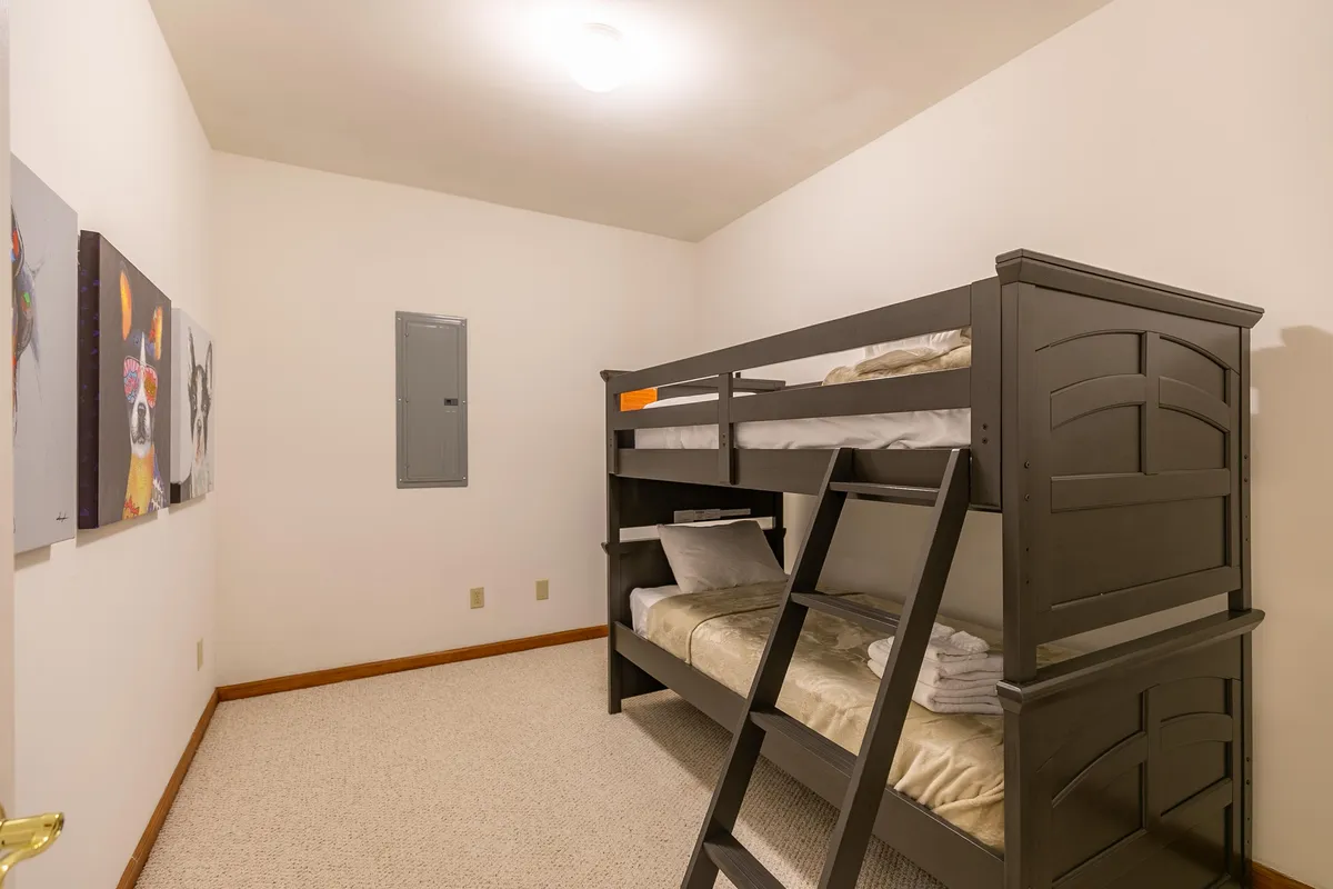 A cozy bonus room equipped with a twin-over-twin bunk bed, playful artwork on the wall, and warm lighting. The inviting environment is perfect for children or extra guests, offering both comfort and a sense of fun.